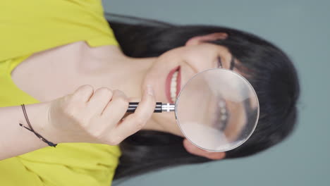 Vertical-video-of-Woman-looking-at-camera-with-magnifying-glass.